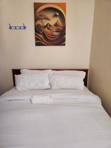 a bed with white sheets and a painting on the wall at Yara Homes in Machakos