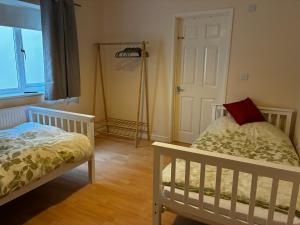a bedroom with two beds and a window and a door at Between the Moors Hideaway in High Bickington +7 photos