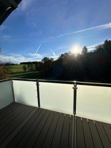 a wooden deck with the sun in the sky at Stylische Ferienwohnung in Salzburg