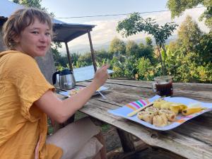 a woman sitting at a picnic table with a plate of food at Sipi Backpackers in Kapchorwa