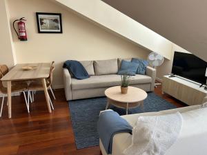 salon z kanapą i stołem w obiekcie Ático en el centro de Llanes w mieście Llanes