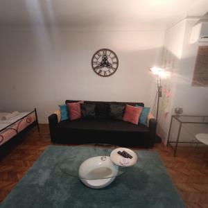 Una sala de estar con un sofá y un reloj en la pared. en Budapest A+ Apartment, en Budapest