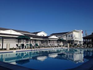 a swimming pool with chairs and umbrellas next to a building at Atlantic Coast Inn in Fenwick Island