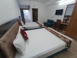 a hotel room with two beds and a couch at Hotel D Palace in Dhaka