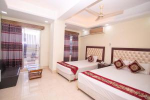 a hotel room with two beds and a window at Hotel D Palace in Dhaka