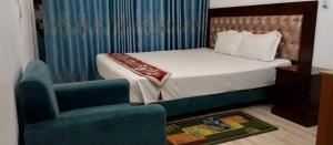 a bedroom with a bed and a chair and a couch at Hotel D Palace in Dhaka