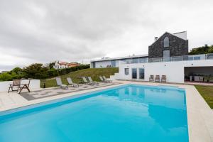 a swimming pool with chairs and a building at Grande Mar Villa in Ponta Garça +99 photos