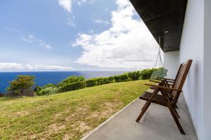 a bench sitting on the side of a building with the ocean at Grande Mar Villa in Ponta Garça