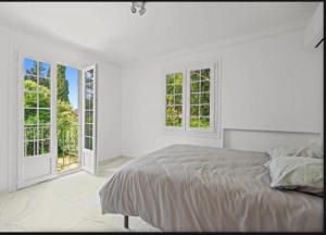 a white bedroom with a bed and two windows at Premium house in Mougins with Private Tennis in Mougins +8 photos