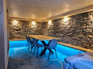 un tavolo e delle sedie in una stanza con un muro di pietra di Chalet Le Monastère a Nendaz