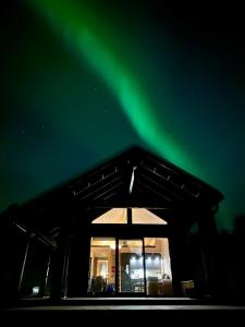 une maison avec des lumières vertes du nord dans le ciel dans l'établissement Welcome to Uppana, à Rovaniemi