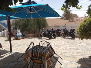 a table and chairs under an umbrella next to motorcycles at dar fatma matmata in Matmata