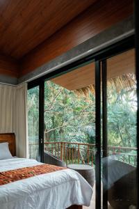 a bedroom with a bed and a large window at Ningmas Escape by Sidhi Hospitality Experiences in Ubud
