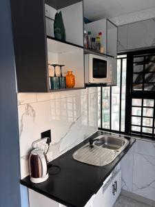 Una pequeña cocina con fregadero y microondas. en Brown Accomodation, en Cape Town 1 foto más