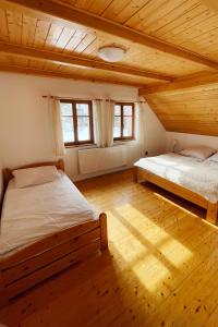 two beds in a room with wooden floors and windows at Chalupa Helena in Vítkovice +12 photos