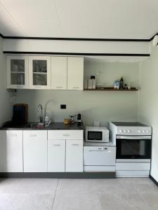 a white kitchen with white cabinets and a microwave at Olden Apartment with Panorama view in Olden