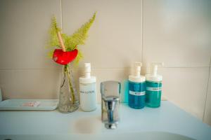 a counter with three bottles of soap and a vase with flowers at The Waves Beach Chalets in Tangalle +89 photos