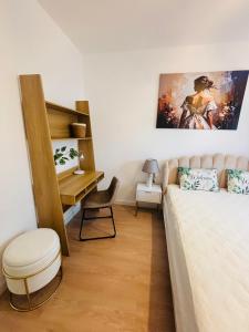 a bedroom with a bed with a desk and a painting on the wall at Lotus Apartments Impero oddzielna kuchnia 2 pokoje garaż in Ostrołęka