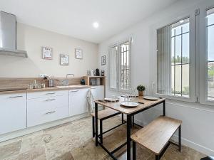a kitchen with a table and a sink and some windows at Lakanaille - Appartement proche du centre - Wifi et Climatisation in Narbonne