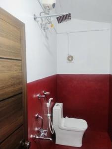 baño con aseo y pared roja en Maanasam Farmstay - Boutique 3BR Countryside Villa, Manikkadavu, en Irrity