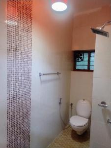 Un baño con inodoro y ducha en Maanasam Farmstay - Boutique 3BR Countryside Villa, Manikkadavu, en Irrity