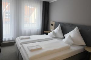 a bedroom with two beds and two windows at HI Grand City Hotel in Hannover