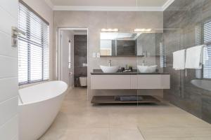 a bathroom with two sinks and a bath tub at Relax in comfort and style with a swimming pool, aircons and braai room in Hermanus +56 photos