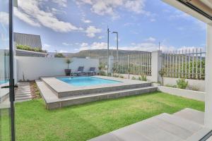 a backyard with a swimming pool and a lawn at Relax in comfort and style with a swimming pool, aircons and braai room in Hermanus