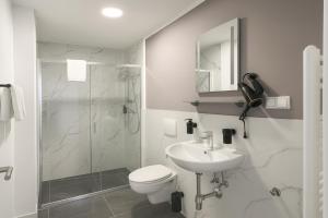 a bathroom with a toilet and a sink and a shower at HI Grand City Hotel in Hannover
