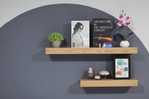 a shelf on a wall with pictures and a book at Ananta House in Bang Su