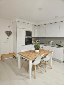 eine Küche mit einem Holztisch und weißen Schränken in der Unterkunft Me&You - Apartamento em Sesimbra - 5 minutos a pé da praia in Sesimbra