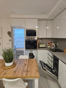 una cucina con un tavolo in legno e mobili bianchi di Me&You - Apartamento em Sesimbra - 5 minutos a pé da praia a Sesimbra