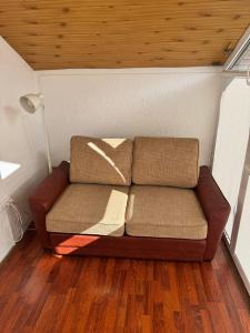 a couch in a room with a wooden ceiling at Saules namu kambariukas in Palanga