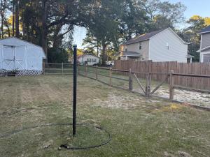 a pole in the middle of a yard with a fence at Casa Minimal Cottage Pet Friendly with Fenced Yard in Raeford