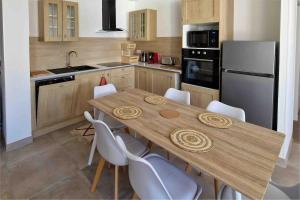 - une cuisine avec une table en bois et des chaises blanches dans l'établissement La Cime Appart Neuf au Port, Clim, Wifi, Parking, Plage, à Valras-Plage
