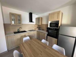 une cuisine avec une table et un réfrigérateur blanc dans l'établissement La Cime Appart Neuf au Port, Clim, Wifi, Parking, Plage, à Valras-Plage 10 autres photos