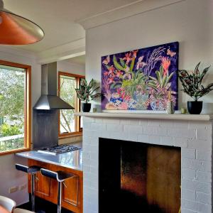 a living room with a fireplace with a painting on the wall at Jerrinja - Absolute waterfront with jetty - 5 mins to Hyams Beach in Erowal Bay +26 photos