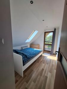 Un dormitorio con una cama con edredón azul y una ventana. en Dom u Julii Bieszczady, en Ustrzyki Dolne