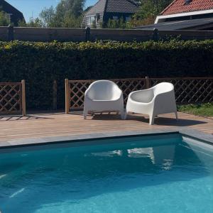 2 sedie bianche sedute accanto alla piscina di Hoeve Altena Cottage a Woudrichem
