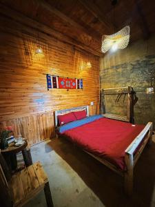 a bedroom with a red bed in a wooden wall at Amazing Lô Lô Chải Homestay in Dồng Văn