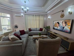 ダル・エス・サラームにあるSami BnB - Apt 04 Makongo after Mlimani Cityのソファと壁掛けテレビのあるリビングルーム