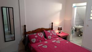 a bedroom with a bed with pink sheets and pink pillows at Mandariniers 97232-3 in Le Lamentin
