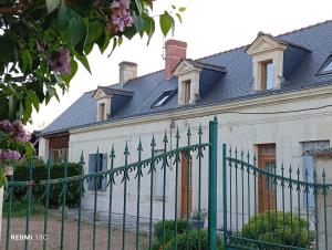 a green fence in front of a white house at Gîte 3 chambres dans Longère aux Rosiers-sur-Loire in Le Thoureil
