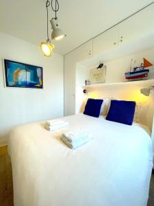 una camera da letto con un grande letto bianco con cuscini blu di Appartement bord de Mer ・Le rivage・ a Piriac-sur-Mer