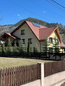 a house with a red roof and a fence at Cabana Plapumioara in Crucea