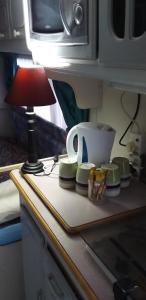 a table with a lamp and dishes on a counter at 10 on the De Villiers Caravan in Winburg