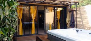 a bath tub sitting next to a house with yellow curtains at Casa Lova Spa Privé, Clim,Baignoire balnéo in Entraigues-sur-la-Sorgue