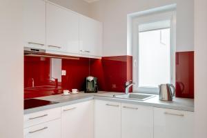 コウォブジェクにあるApartament w Rezydencji Maritimoの白いキャビネットと赤い壁のキッチン
