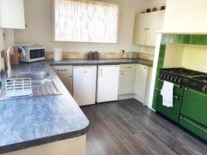 a kitchen with white cabinets and a green stove top oven at Hawthorn Valley Views in Wroxall +10 photos