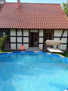 a swimming pool in front of a house with a tile roof at Siedlisko Wilczyny 